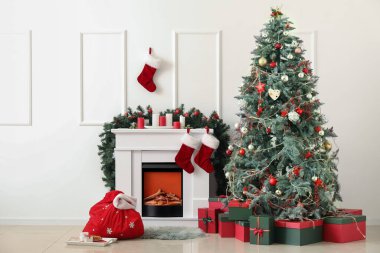 Noel Baba çantası, şömine ve Noel ağacıyla aydınlık oturma odasının içinde.
