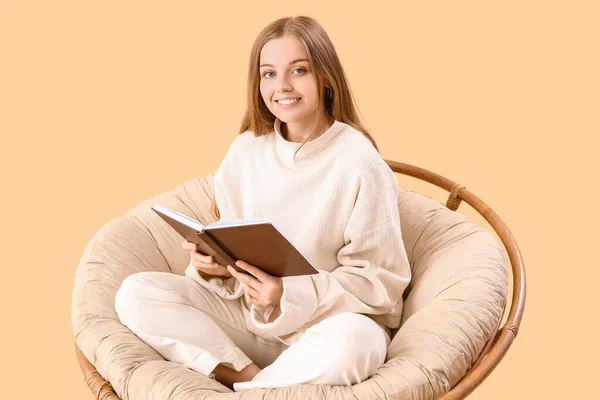 Νεαρή Γυναίκα Βιβλίο Κάθεται Στην Πολυθρόνα Μπεζ Φόντο — Φωτογραφία Αρχείου