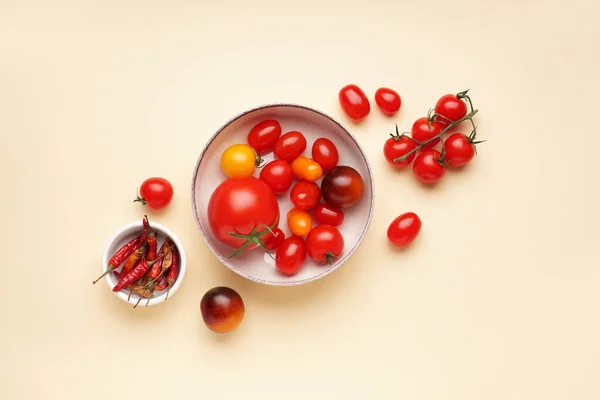 Bowl with different fresh tomatoes on color background