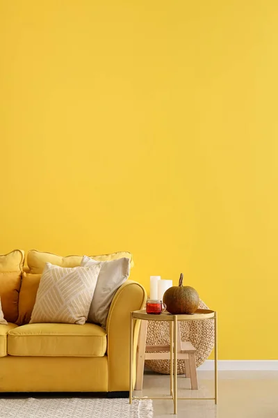 Interior of bright living room with yellow sofa, table and pumpkin