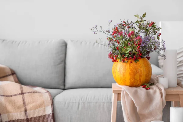 リビングルームの脚立の上に秋の花やろうそくとカボチャ — ストック写真