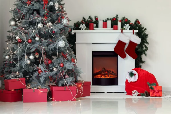 光の壁の近くの暖炉とクリスマスツリー付きのサンタバッグ — ストック写真