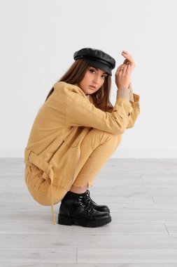 Güzel, modaya uygun, hafif arka planda günlük kıyafetler giyen genç bir kadın.