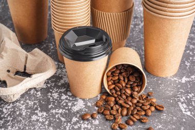 Farklı kağıt bardaklar ve arkaplanda kahve çekirdekleri.