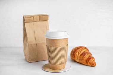 Kağıt bardak, poşet ve kruvasan.