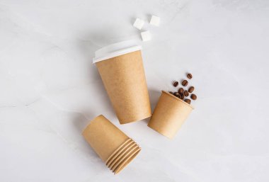 Kahve çekirdekli kağıt bardaklar ve hafif arka planda şeker.