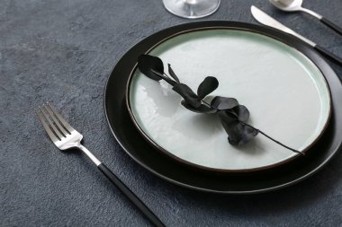 Koyu arkaplanda okaliptüs dalı olan şık masa ayarları, yakın plan