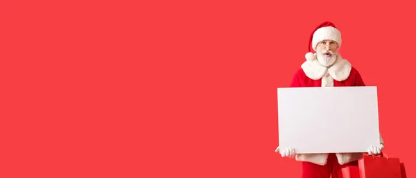 Überraschter Weihnachtsmann Mit Leerem Poster Und Einkaufstaschen Auf Rotem Hintergrund — Stockfoto