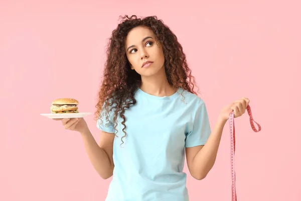 Junge Afroamerikanerin Mit Burger Und Maßband Auf Rosa Hintergrund Ernährungskonzept — Stockfoto