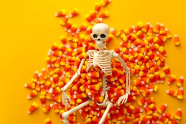 Sarı arka planda iskeleti olan Cadılar Bayramı şekerleri.