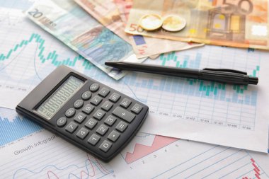 Şemalarda para ve kalem olan hesap makinesi, yakın plan. Değişim oranı kavramı
