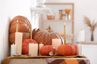 Yanan mumlarla taze balkabakları ve mutfak tezgahında düşen yapraklar.