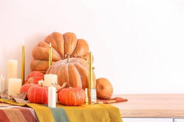 Yanan mumlarla taze balkabakları ve mutfak tezgahında düşen yapraklar.