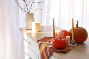 Mutfak tezgahında yanan mumlar ve peçetelerle taze balkabakları, yakın plan.