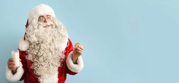 Papai Noel Segurando Biscoito Saboroso Vidro Leite Fundo Azul Claro — Fotografia de Stock
