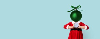 Noel Baba kostümlü küçük kız, kafası yerine Noel topuyla açık mavi arka planda mesaj için yeri olan.