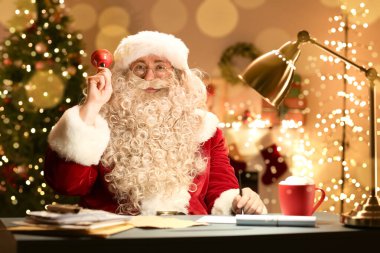Noel çanı çalan Noel Baba akşam masada oturuyor.