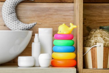 Bebek banyosu aksesuarları ve tahta duvarın yanındaki masada oyuncaklar.