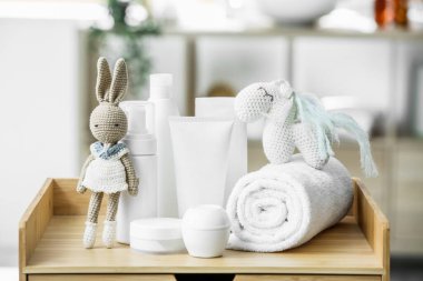 Sevimli oyuncaklar ve banyodaki ahşap masanın üzerindeki çocuklar için farklı banyo aksesuarları.