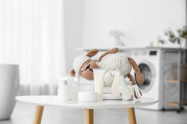 Çocuklar için farklı banyo aksesuarları ve hafif banyodaki masada sevimli oyuncaklar.