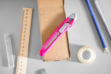 Gri arka planda karton kutulu pembe alet bıçağı, yakın plan.