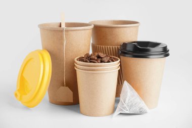 Beyaz arka planda kağıt bardaklar, çay poşetleri ve kahve çekirdekleri.