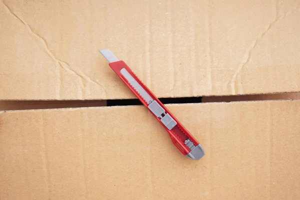 Utility knife on cardboard box, top view