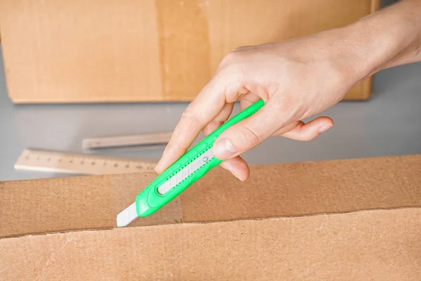 Man Opening Cardboard Box Utility Knife Grey Background Closeup — Stock Photo, Image