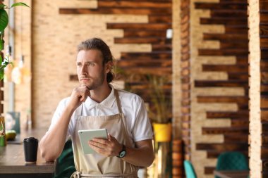 Kafesinde tablet bilgisayarı olan düşünceli bir işletme sahibi.