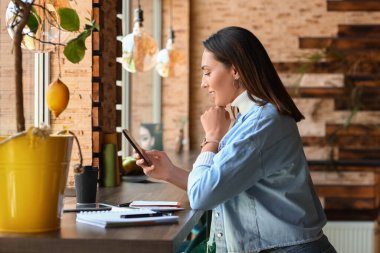Kafesinde cep telefonuyla çalışan güzel bir işyeri sahibi.