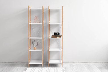 Dekorlu raflar, fotoğraf makinesi ve ışık duvarına yakın kitaplar.