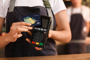 Kafede kredi kartı ve ödeme terminali olan genç bayan barista, yakın plan.