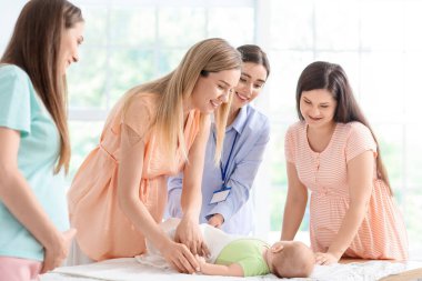 Kadın konuşmacı müstakbel annelere bebeği kundaklamayı öğretiyor.