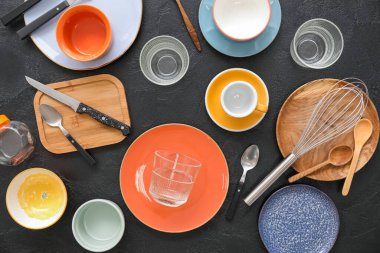 Koyu arkaplanda birçok farklı sofra takımı ve mutfak malzemesi, üst görünüm