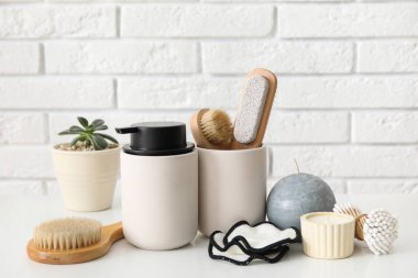 Masanın üzerinde hafif tuğla duvara karşı banyo malzemeleri var.