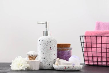 Işık duvarının yanındaki masada banyo malzemeleri var.