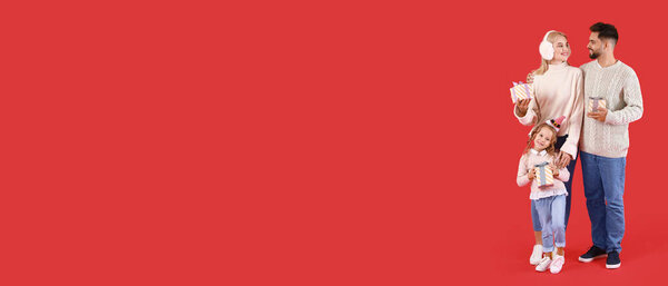 Happy family with Christmas gifts on red background with space for text