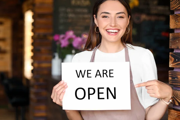 Beautiful business owner with opening sign in her cafe