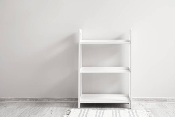 Empty white shelving unit near light wall