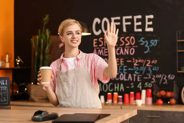 Jonge Vrouwelijke Barista Met Kopje Koffie Zwaaiende Hand Cafe — Stockfoto