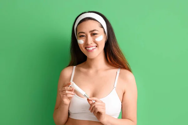 緑の背景に顔のマスクを持つ美しい若いアジアの女性 — ストック写真