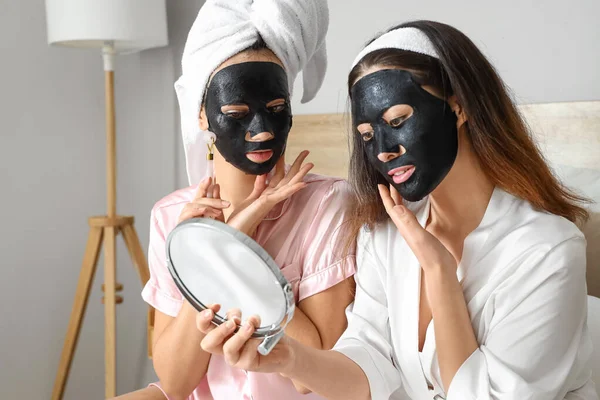 Vackra Unga Kvinnor Med Aktiverad Träkol Blad Ansiktsmasker Sovrummet — Stockfoto