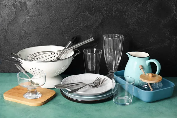 Set of different dishware and kitchenware on green table