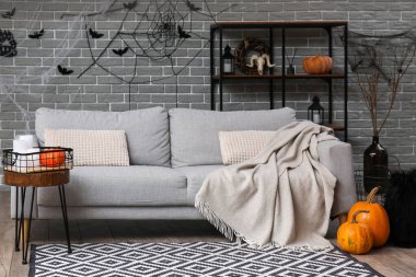 Gri kanepe ve raf ünitesiyle Cadılar Bayramı için dekore edilmiş oturma odasının içi.