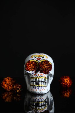 Meksika Ölüler Günü (El Dia de Muertos) için boyalı kafatası ve siyah arka planda kadife çiçekleri