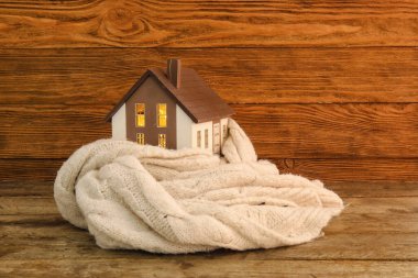 Koyu ahşap arka planda örülmüş eşarplı ev modeli. Isıtma kavramı