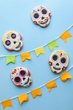 Kafatası şekilli kurabiyeler ve mavi arka planda bayraklar. El Dia de Muertos