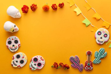 Kurabiyelerden, kafataslarından, bayraklardan ve turuncu arka plandaki çiçeklerden yapılmış çerçeve. El Dia de Muertos