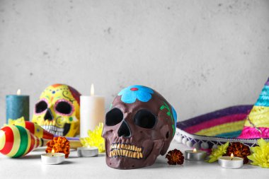 Meksika Ölüler Günü için boyanmış kafatası (El Dia de Muertos), yanan mumlar ve çiçekler arka planda, yakın plan