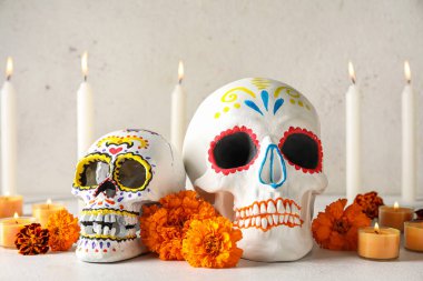 Meksika Ölüler Günü için boyanmış kafatasları (El Dia de Muertos), hafif arkaplanda çiçekler ve mumlar